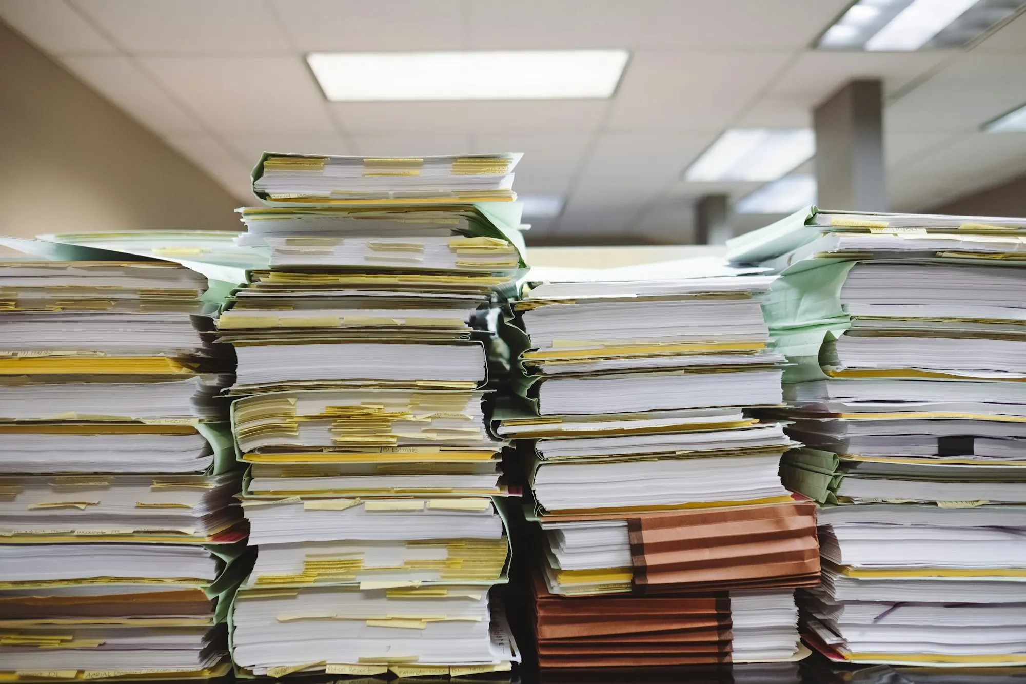 Tall stacks of paper files on an office desk, a reminder of the permit and utility paperwork behind solar removal and reinstall in Alsip